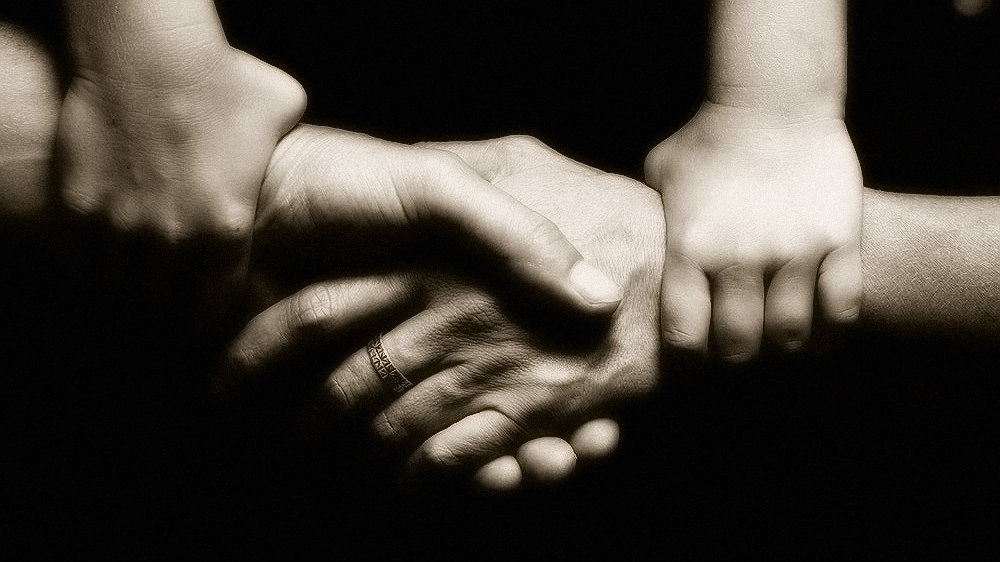baby hands forcing two adult to hold hands
