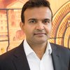 Dr Manish Saxena looking at the camera wearing a white shirt and smart black jacket