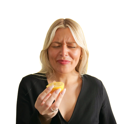 A woman eating a zesty lemon and pulling a sour face